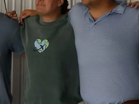Two volunteers stand indoors with their arms around each other's shoulders
