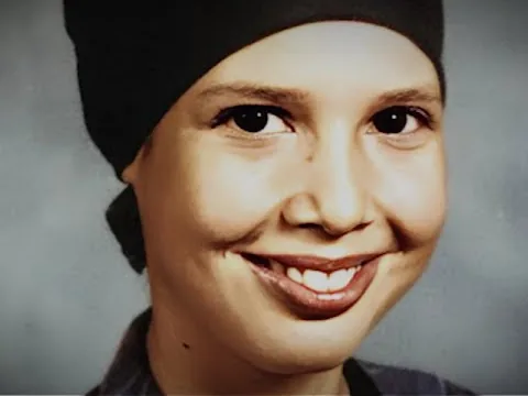 A portrait photograph of a smiling young woman wearing a knitted cap